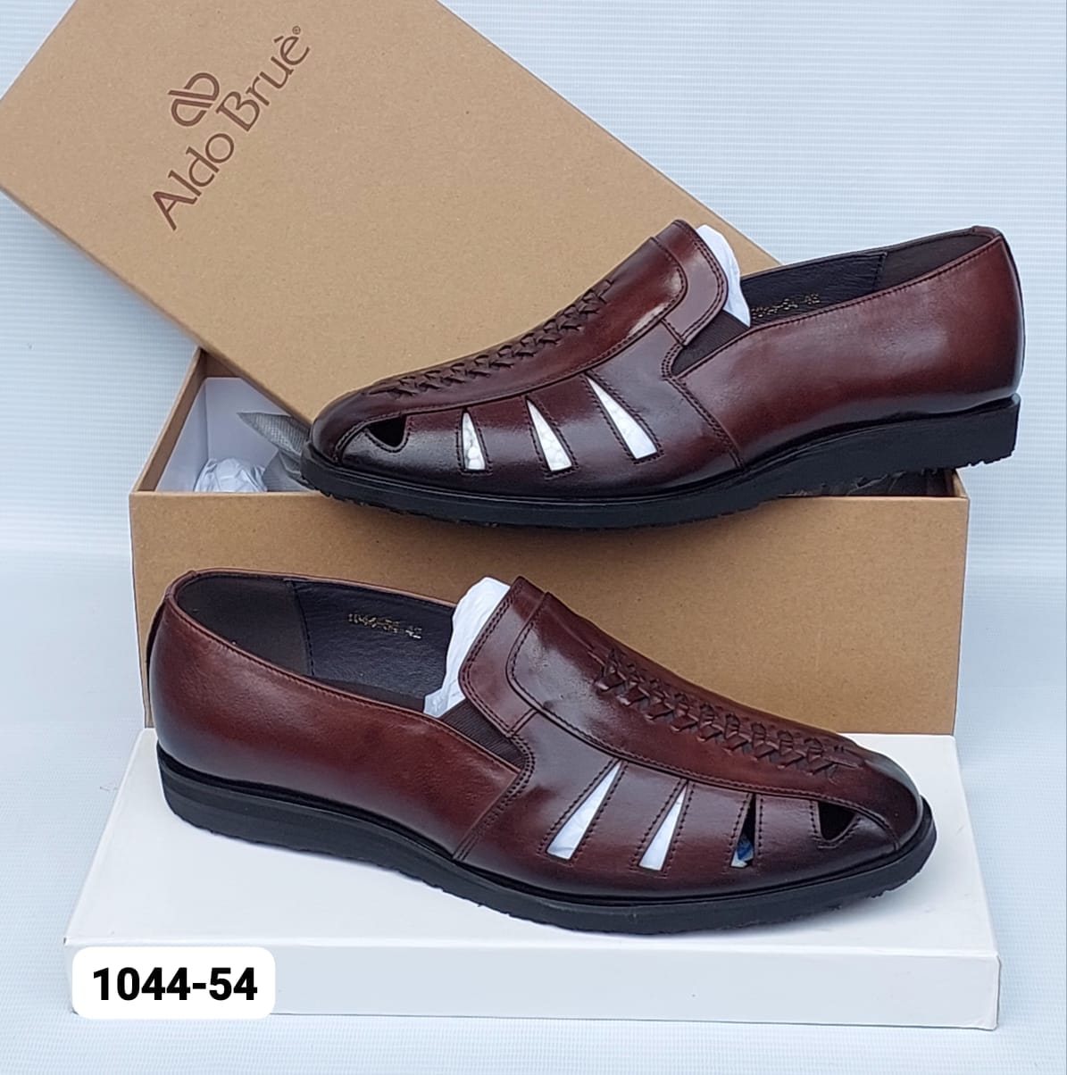 A pair of Aldo Brue men's brown leather slip-on shoes with cutout details, displayed on a white surface with their brown cardboard box behind them. The model number 1044-54 is shown in a white box in the bottom-left corner.