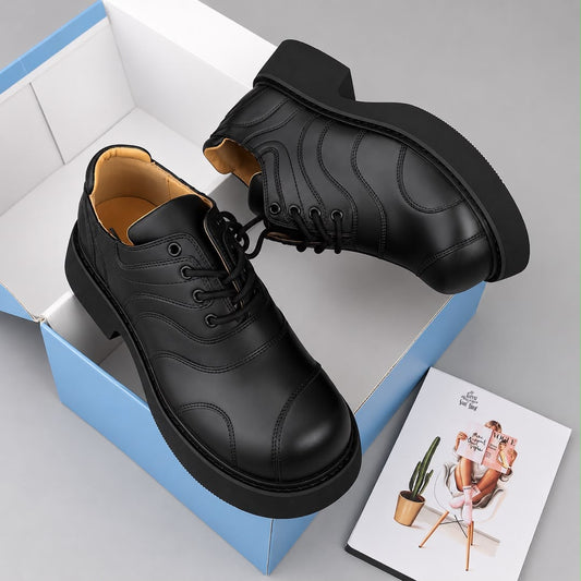 Pair of black panelled men's lace-up shoes with tonal stitched detailing and a substantial black sole in a shoebox