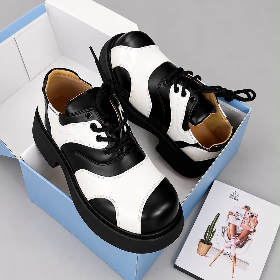 Pair of black and white panelled men's lace-up sneakers displayed in a blue and white shoebox
