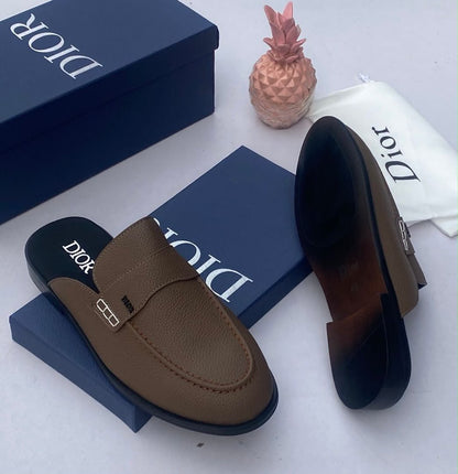 Dior brown pebbled leather mule slides with gold CD buckle hardware, displayed with Dior navy blue box and branded dust bag — 100% authentic men's luxury footwear