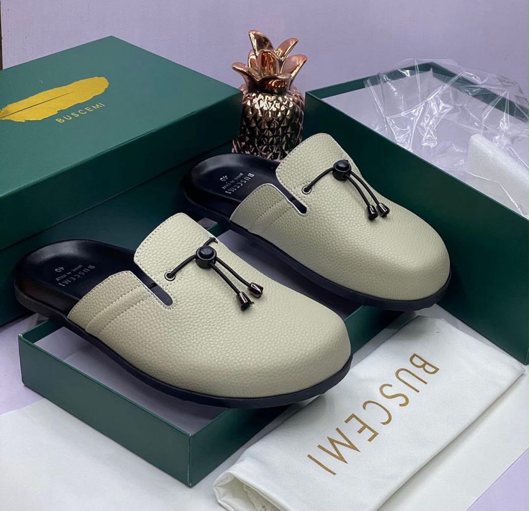 Buscemi cream pebbled leather mule slides with black cord toggle detail, displayed in signature Buscemi green box with dust bag — 100% authentic men's luxury footwear