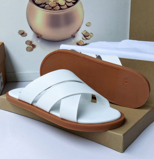 Premium white leather crossband slide sandal with warm tan rubber sole — side and sole view displayed on a kraft box against a neutral background
