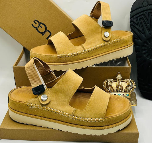 UGG Goldenstar chestnut suede double-strap sandals with UGG logo buckle ankle strap, silver dome stud toe detail, espadrille midsole stitching, and ridged cream outsole on UGG kraft box — 100% authentic men's luxury sandals