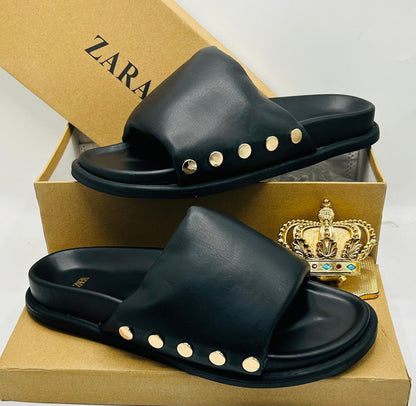 Zara black leather wide-strap slide sandals with gold dome stud embellishments along strap base, displayed on Zara kraft box with gold crown prop — 100% authentic men's luxury slides