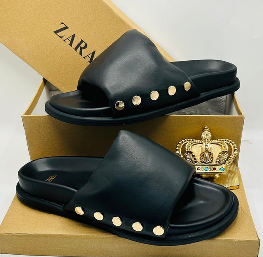 Zara black leather wide-strap slide sandals with gold dome stud embellishments along strap base, displayed on Zara kraft box with gold crown prop — 100% authentic men's luxury slides