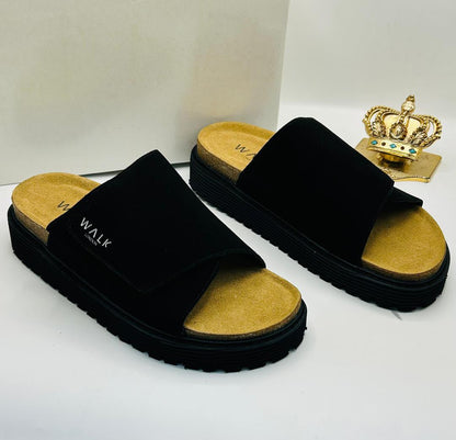 Walk London black suede wide single-strap platform slides with WALK LONDON embroidered wordmark in white, natural cork-effect tan footbed, and chunky black ridged rubber outsole on white box with gold crown prop — 100% authentic men's luxury slides