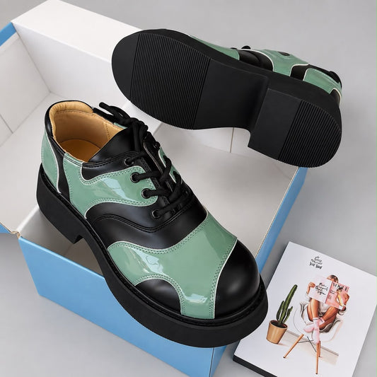 Pair of green and black panelled men's lace-up sneakers with a ribbed black sole in a shoebox